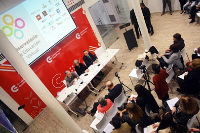 Sala de conferencia con participantes, pantalla y mesa de exposición