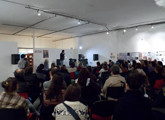 Salón de Punto de encuentro con artistas leyendo y público sentado observando